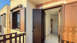 Ein Wohngebäude mit Balkon, einer Holztür und gefliestem Boden.