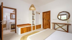 Quarto com cama, guarda-roupa de madeira, mesa de cabeceira e espelho.