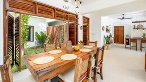 Uma sala de jantar com uma mesa de madeira, cadeiras e um ventilador de teto.