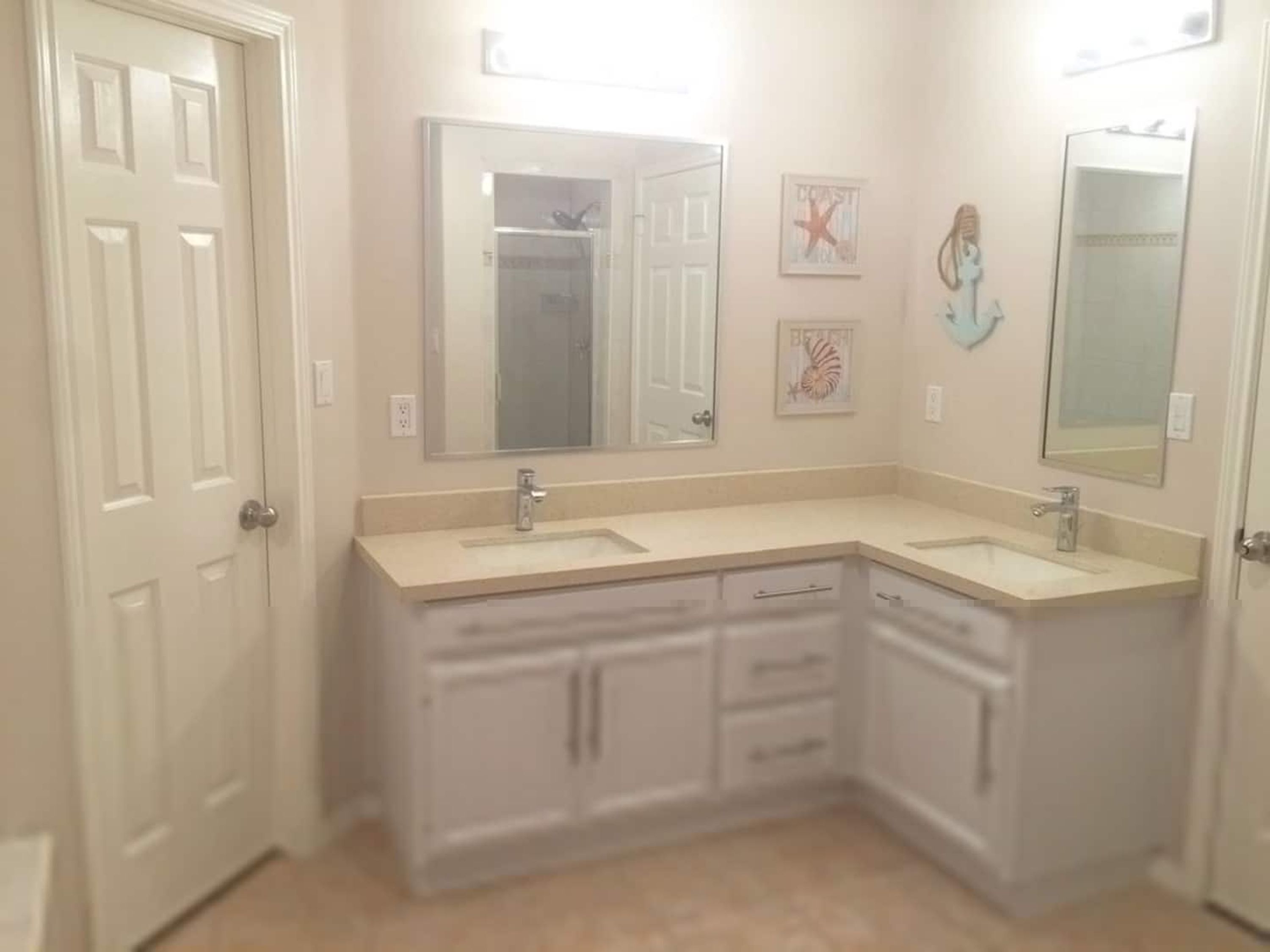 A bathroom with two sinks, a walk-in closet, and a large mirror.