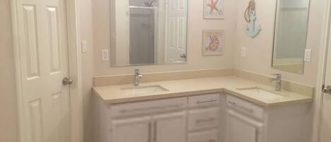 A bathroom with two sinks, a walk-in closet, and a large mirror.