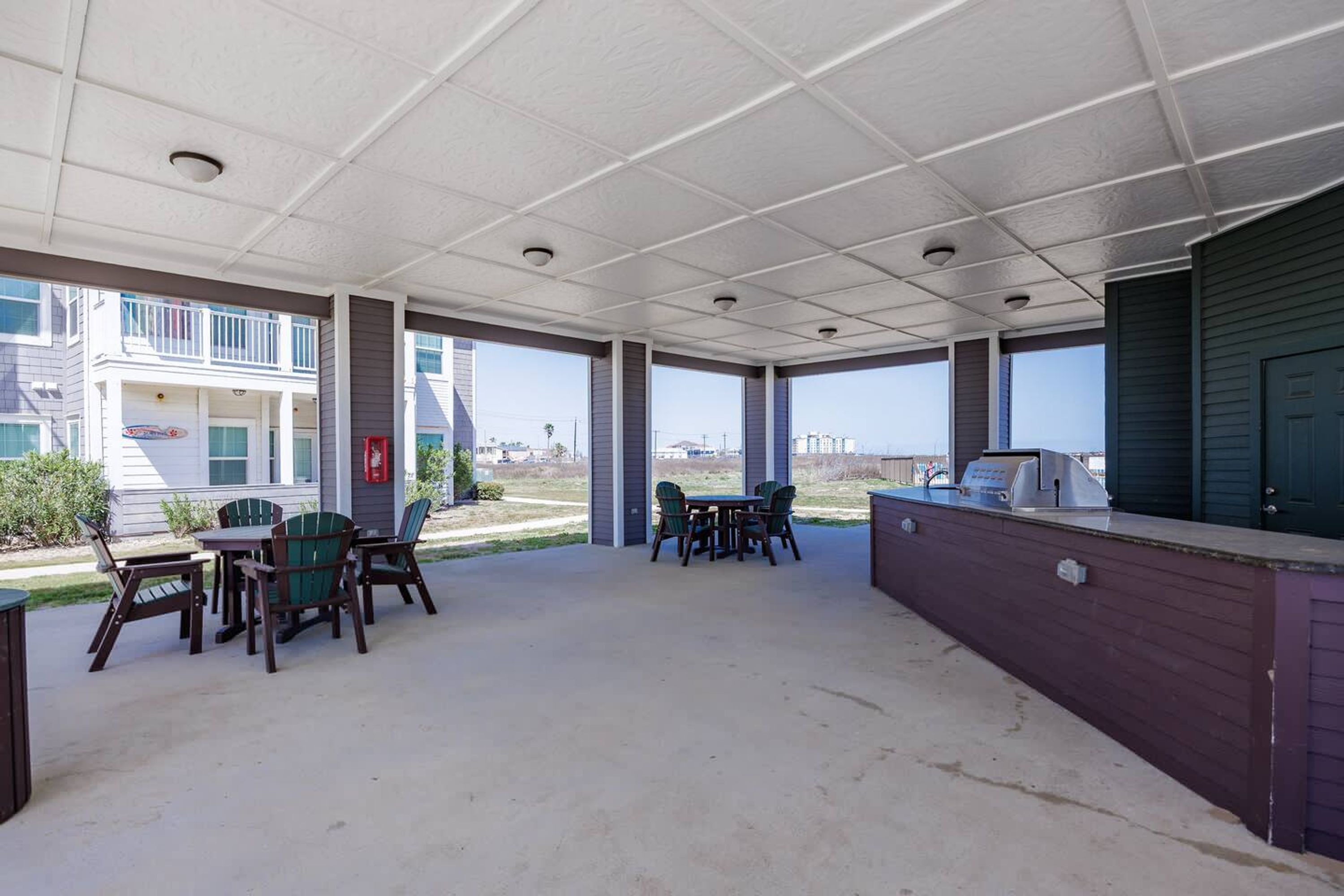 Un patio al aire libre con mesas, sillas, una parrilla y vistas de los edificios circundantes.