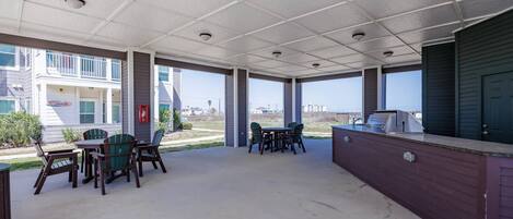 Un patio al aire libre con mesas, sillas, una parrilla y vistas de los edificios circundantes.