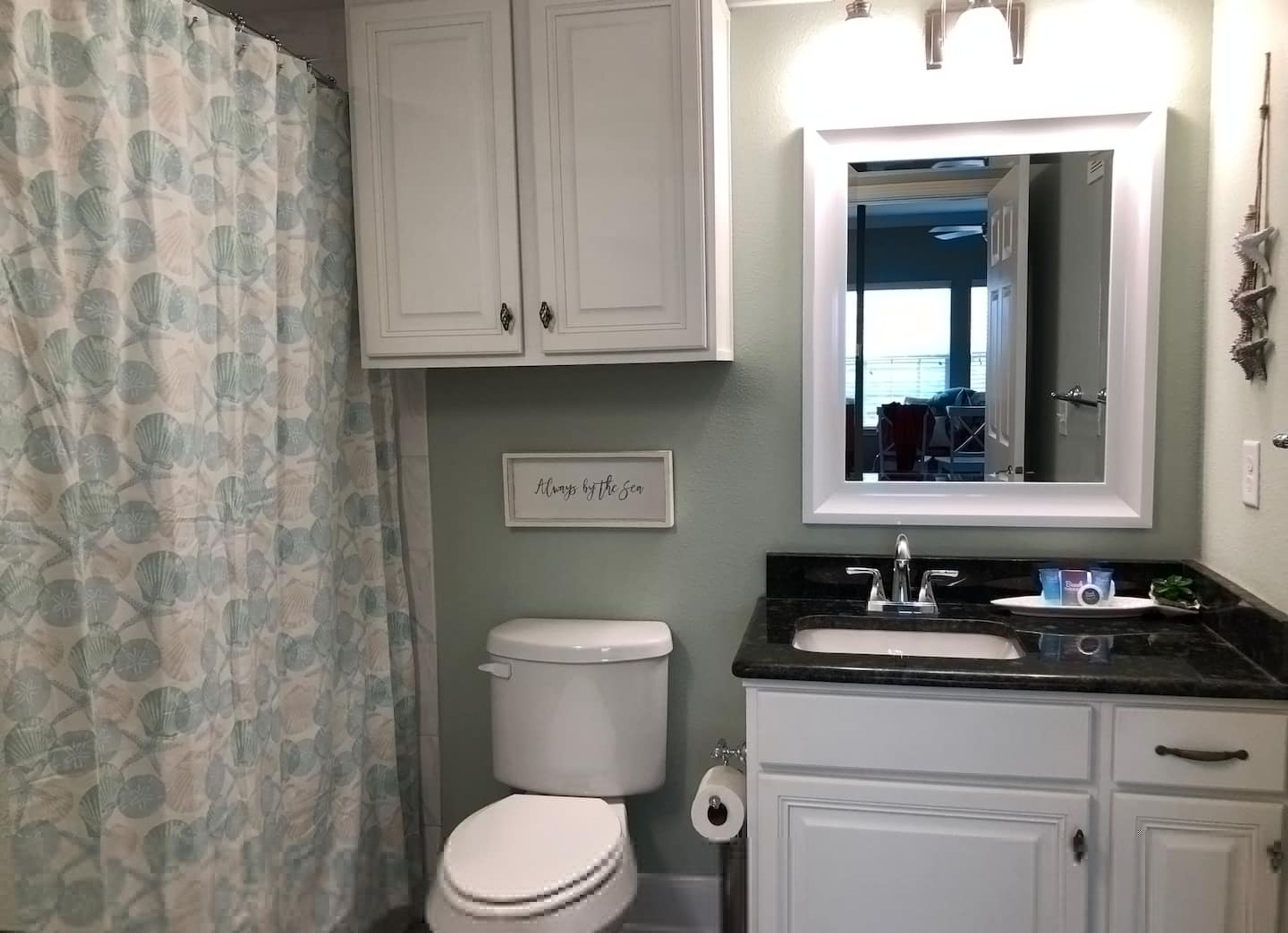 A bathroom with a toilet, sink, and mirror.