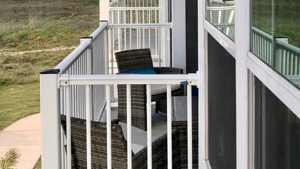 A balcony with a view of the beach, a chair, and a railing. - Private Path to Whitecap Beach Pool 5 Stars (Corpus Christi)