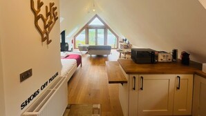 Een slaapkamer in loftstijl met dakraam, een kitchenette en uitzicht op het groen.