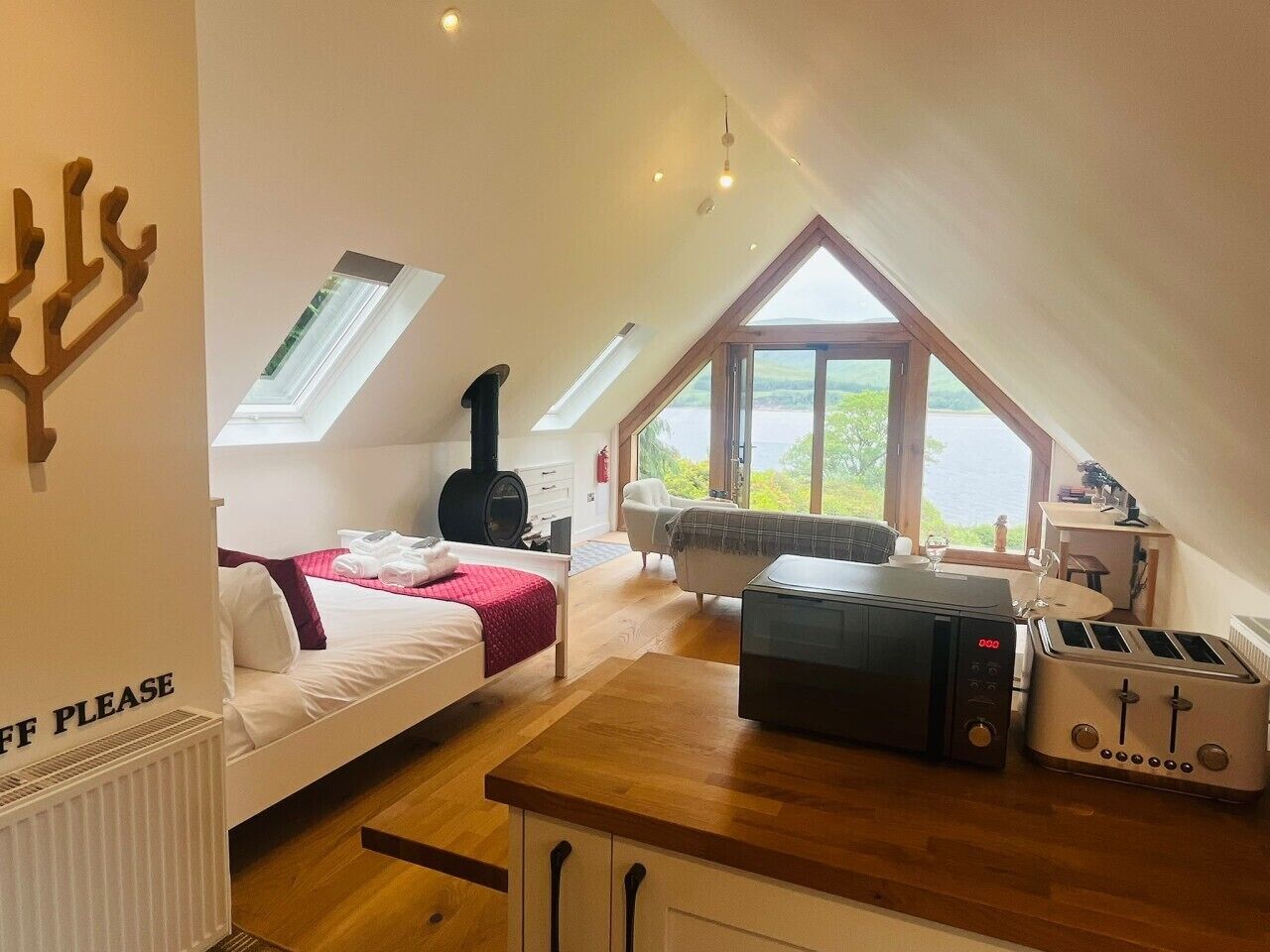 Een gezellige kamer met een bed, een tafel met een broodrooster, een open haard en uitzicht op de natuur.