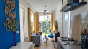 Una cocina moderna con estufa a gas, un comedor con mesa y sillas blancas, y una sala de estar con sofá y mesa de centro.