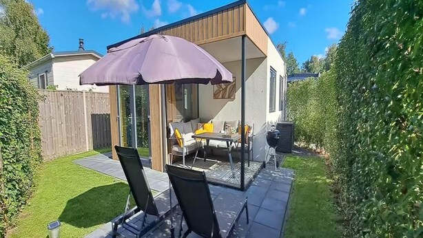 Un patio con mesa y sillas, una parrilla y una zona de estar cubierta.