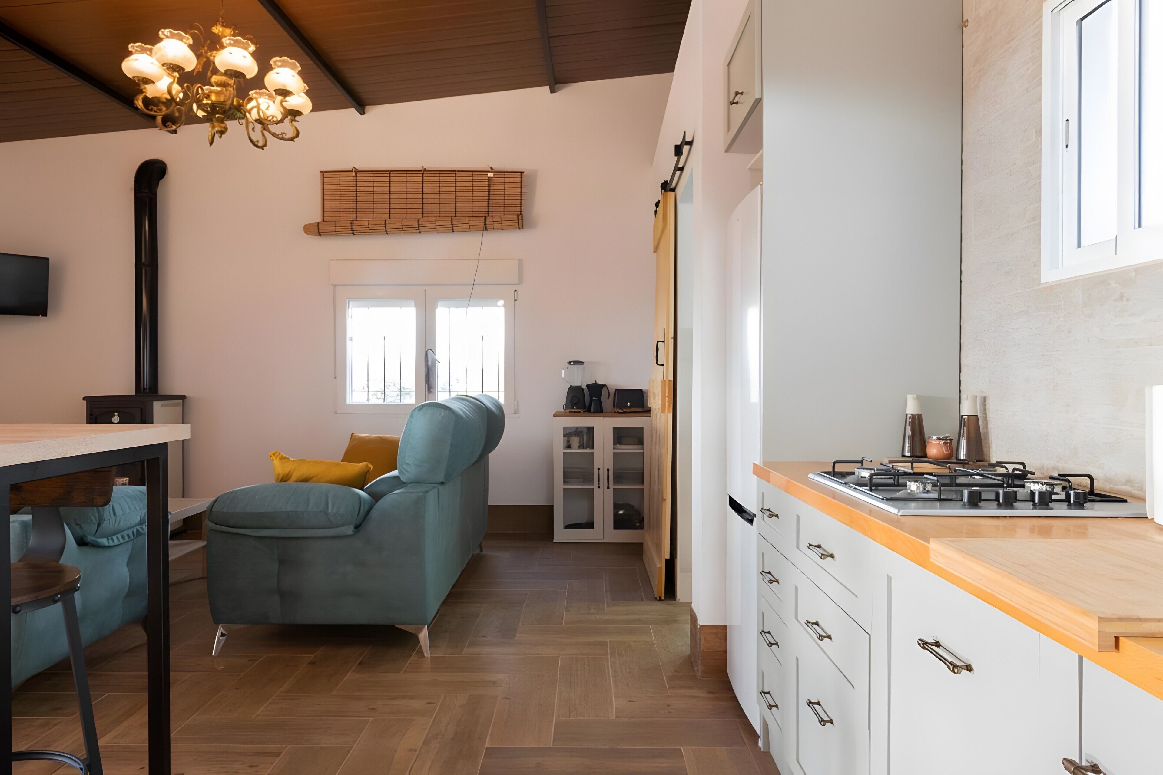 A modern kitchen with a wooden countertop, a built-in stove, and a window with blinds.