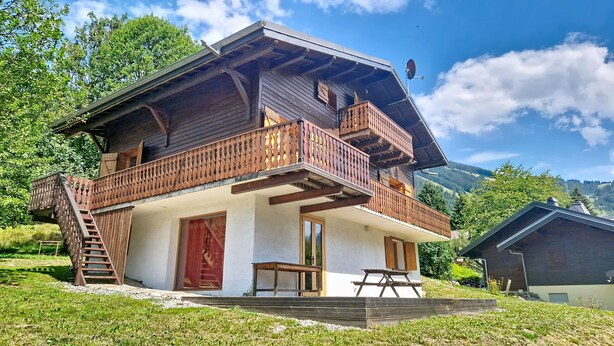 A two-story wooden chalet with a balcony, a staircase, and a picnic table. - Mésanges Chalet MSG NATURE & QUIET (10 people) (Châtel)
