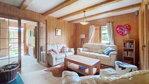 A cozy living room with wooden walls, a white sofa, a coffee table, and a bookshelf. - Mésanges Chalet MSG NATURE & QUIET (10 people) (Châtel)