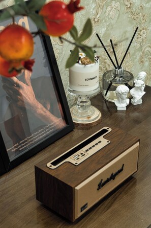 Un tableau encadré, une bougie, un diffuseur et une boîte sur une table en bois.