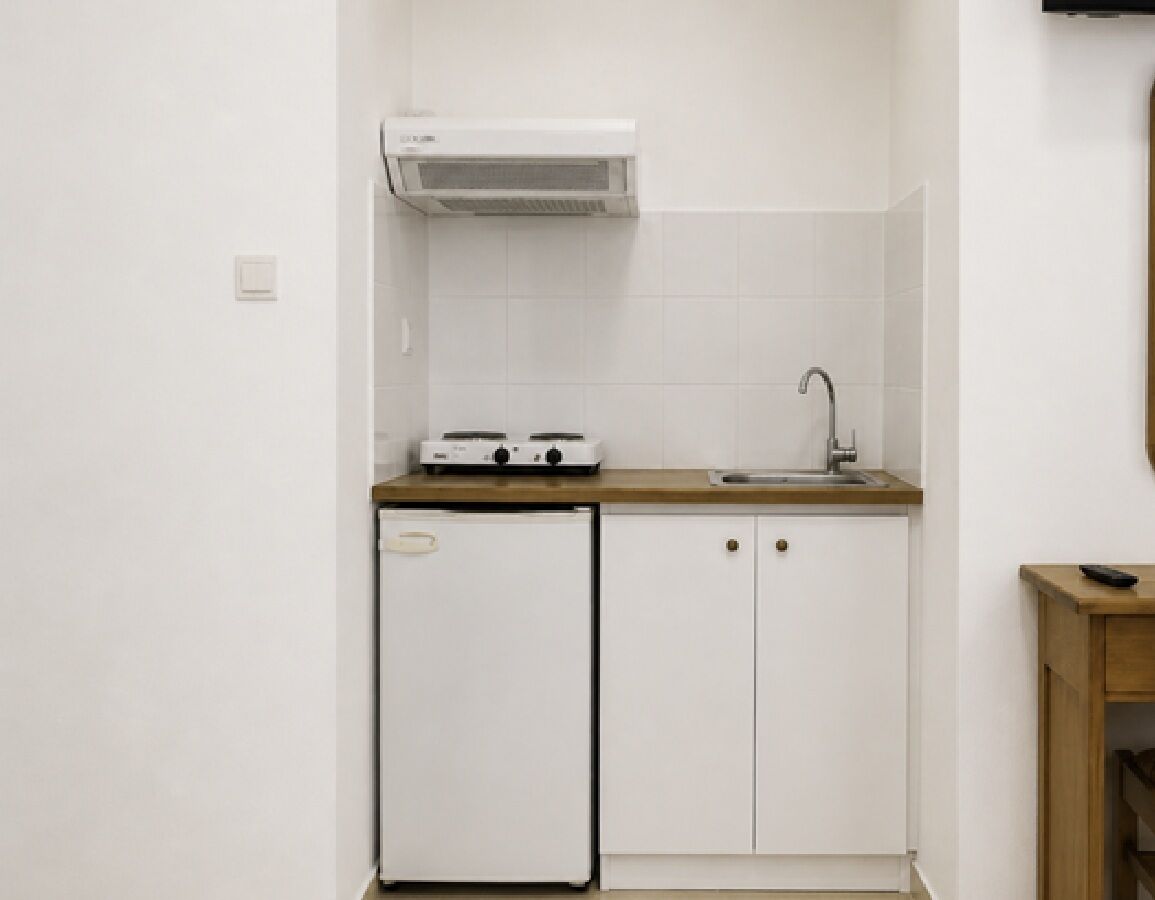 A compact kitchen with a built-in stove, a sink, and a small refrigerator.