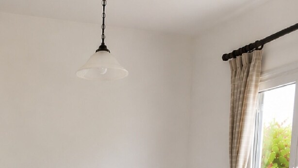 Une chambre avec deux lits, une table de chevet, une lampe suspendue et une fenêtre avec des rideaux.
