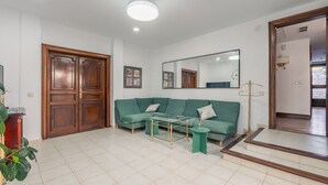 Ein Wohnzimmer mit einem grünen Sofa, einem Glastisch und einer Holztür.