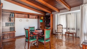 Ein Zimmer mit Holzböcherschränken, einem runden Tisch und grünen Polstersesseln.