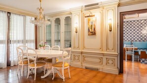 Ein Essbereich mit einem runden Tisch, weißen Stühlen, einer Chandelierleuchte und einer Wand mit Muster.