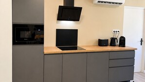 Una cocina moderna con electrodomésticos integrados, encimera de madera y diseño de muebles grises.