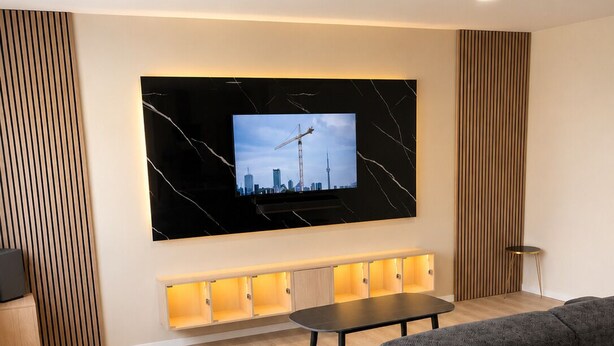 Una sala moderna con un televisor grande, un sofá, una mesa de comedor y una pared decorativa de madera.