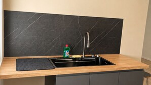 Una cocina moderna con salpicadero de mármol negro, encimera de madera e instalación de lavaplatos integrada.