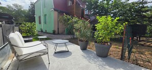 A patio area with a metal chair and a small round table, surrounded by potted plants and a green fence. - Apartment for 6 people near downtown (Colmar)