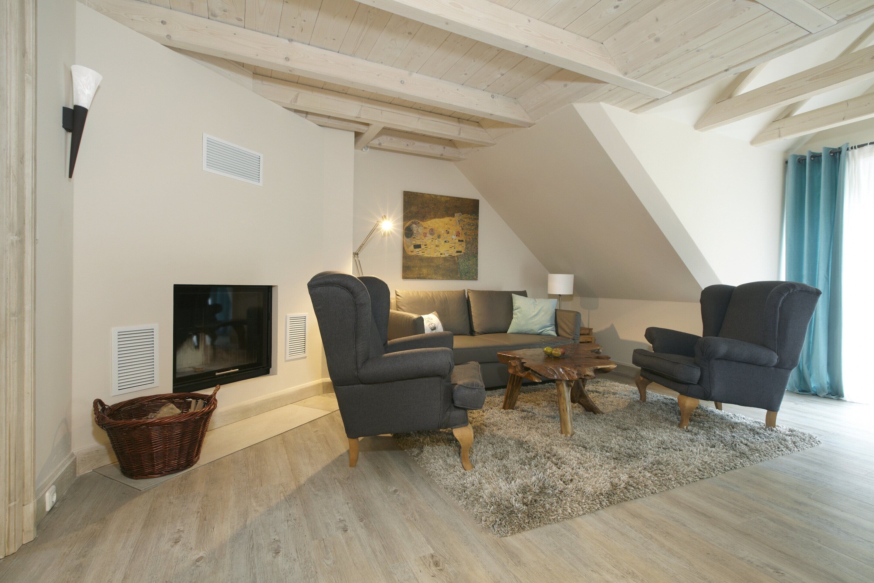 Ein Wohnzimmer mit Fernseher, zwei Sesseln, einer Couch, einem Couchtisch und einem Bild an der Wand.