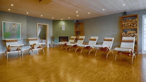 Um quarto com piso de madeira, lareira e uma fileira de poltronas.