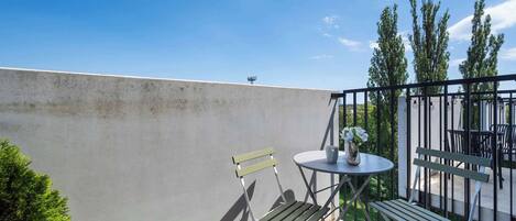 A balcony with a table, chairs, and a potted plant.