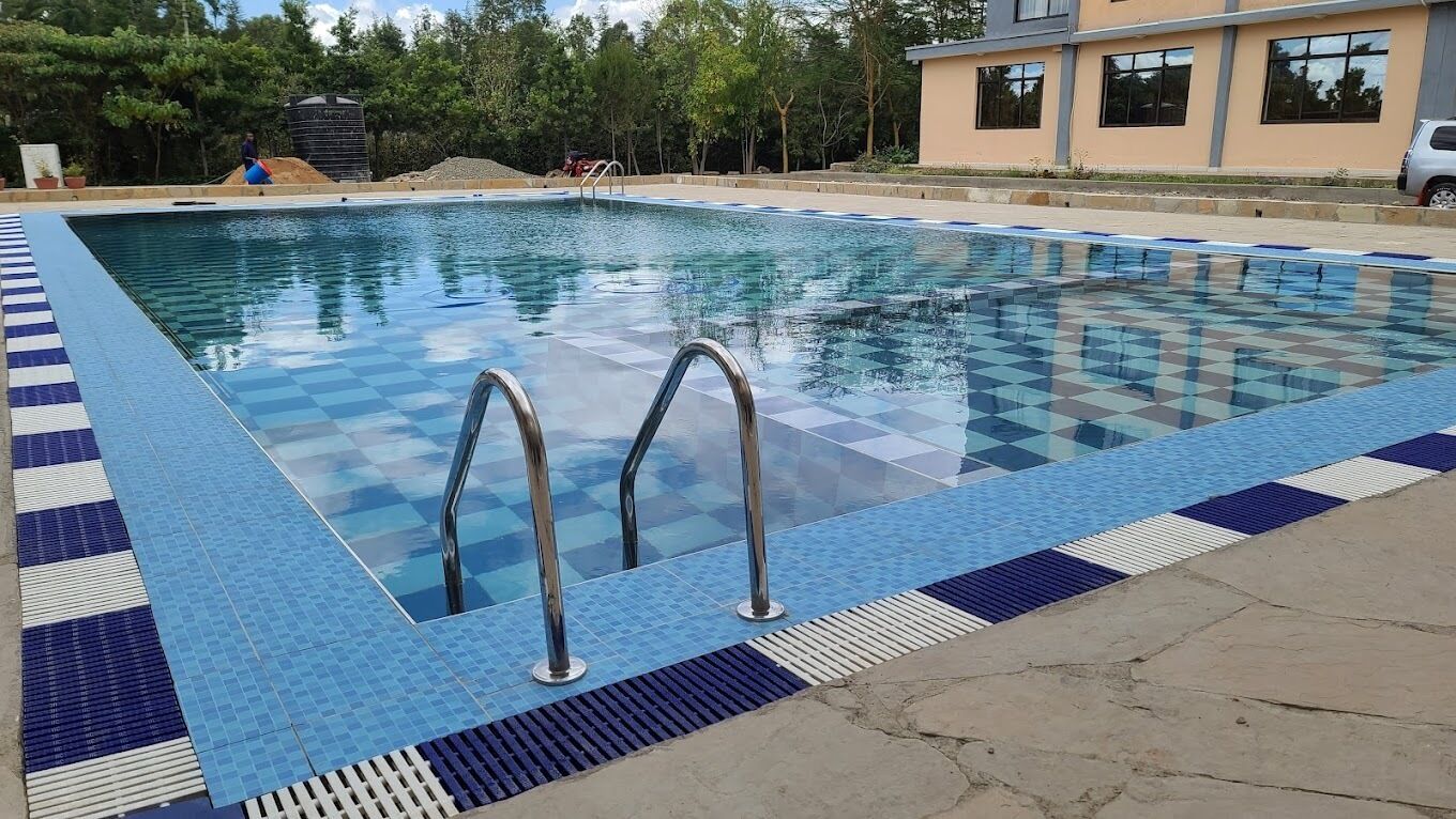 A rectangular swimming pool with a checkered tile pattern and metal handrails.