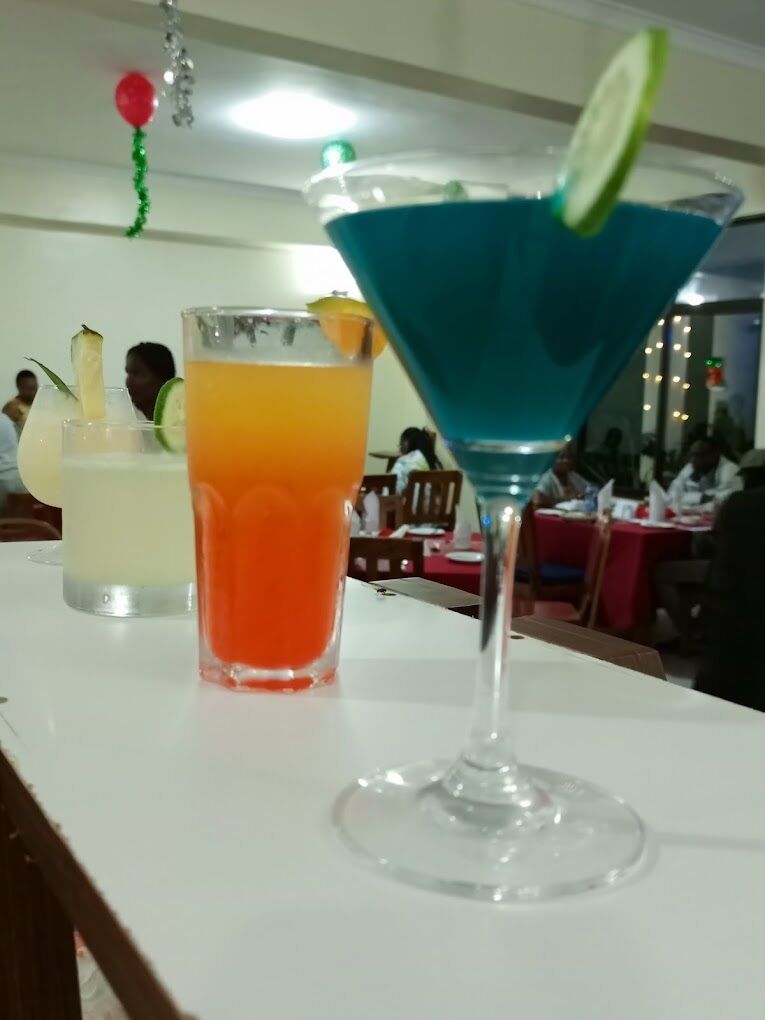 Un coin bar avec un cocktail bleu et un verre de jus d’orange.