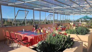 Un invernadero con mesas y sillas, rodeado de plantas.