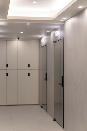 A modern, well-lit hallway with a ceiling camera, a door with a number sign, and a shoe rack. - ZIP1972 Euljiro & Myeong (Seoul)