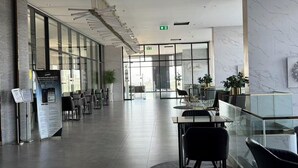 A modern hotel lobby with a glass partition, seating area, and a reception desk. - The Rich Rama 9 - Srinakarin (Khet Suan Luang)