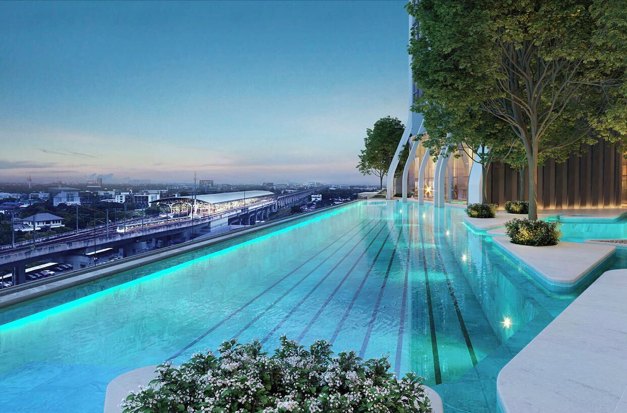 Une piscine à débordement moderne offrant une vue sur la ville, avec un pont en arrière-plan et une terrasse bordée d’arbres.