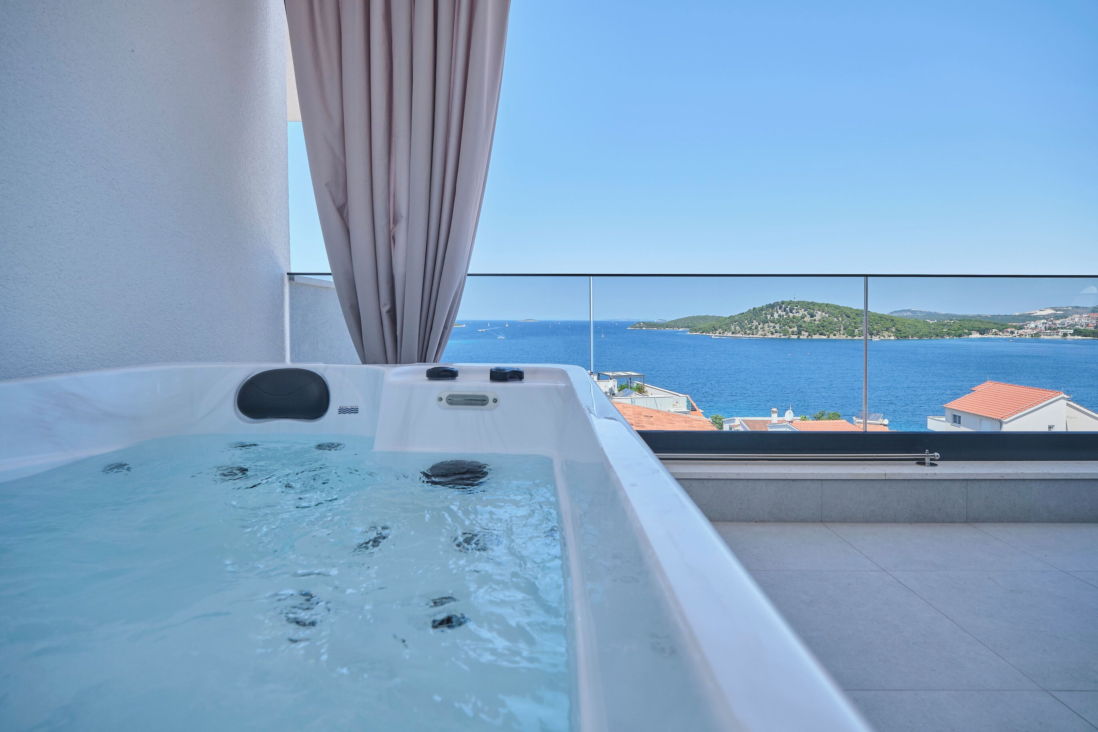 A hot tub on a balcony with a view of the sea and a distant island.
