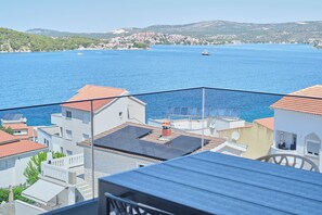 A coastal town with buildings, a clear blue sea, and a boat in the distance. - Apartment Maestral (Ražanj)