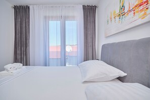 Ein Hotelzimmer mit Bett, einem Fenster mit Vorhängen und einem Bild an der Wand.