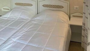 A bed with a white quilted bedspread and headboard with a decorative pattern.