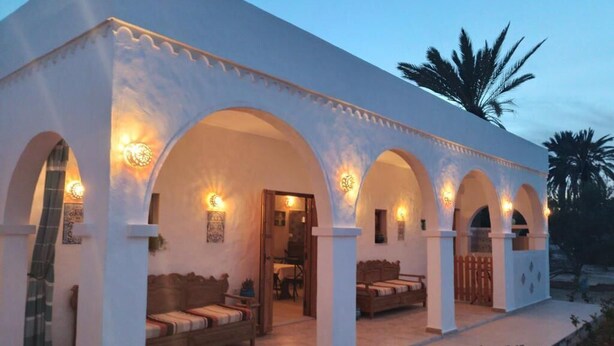 A building with multiple arches, a covered outdoor seating area, and a visible entrance.