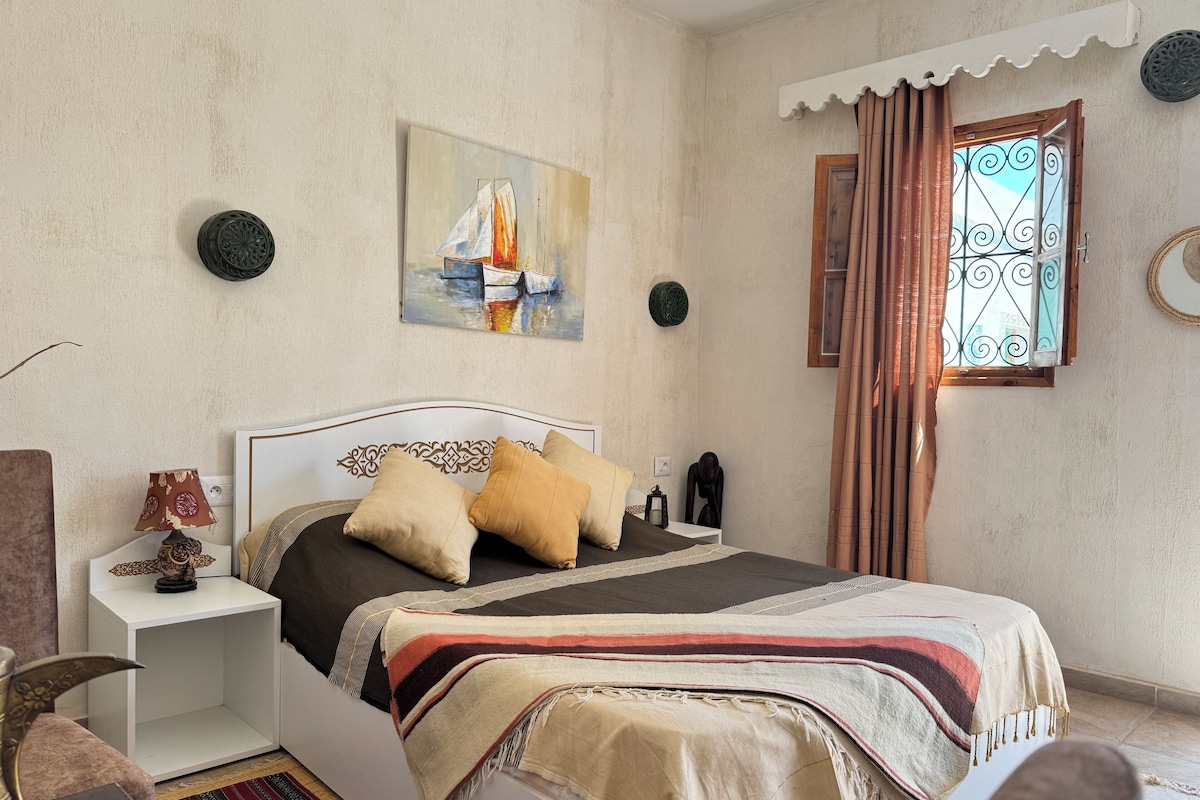 Une chambre à coucher avec un lit, une table de chevet, une lampe et un tableau au mur.