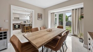 A modern kitchen with a dining area, large windows, and a view of the outdoors. - Spacious Modern home in Whitefield - Sleeps 9 (Whitefield)