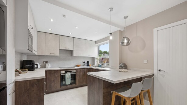 A modern kitchen with a large island, wooden cabinets, and a white door. - Spacious Modern home in Whitefield - Sleeps 9 (Whitefield)