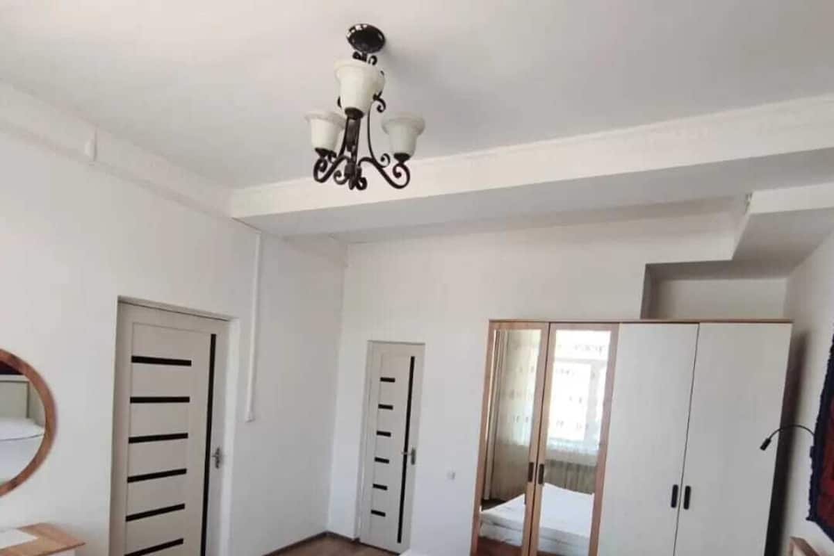 Quarto com cama, guarda-roupa, espelho e lustre.