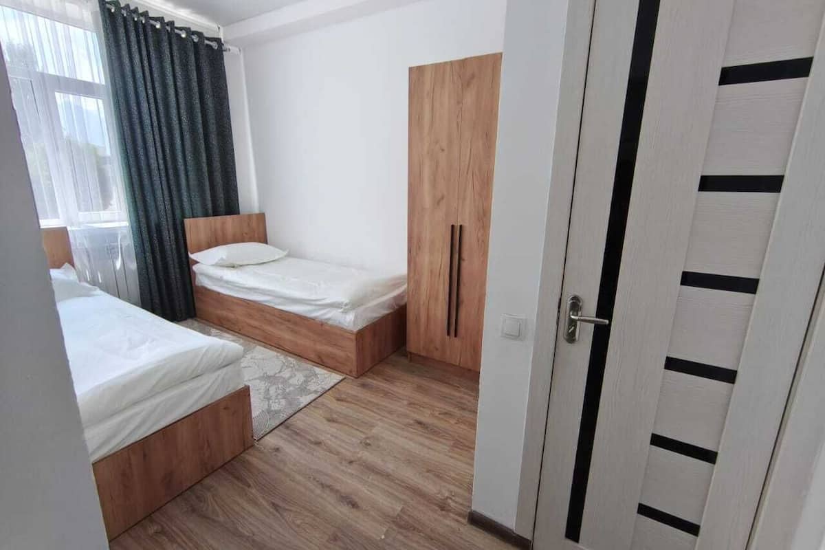 Quarto com duas camas, um guarda-roupa e uma porta.