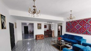 Un amplio salón con piso de mármol, un conjunto de sofá azul, una mesa de centro y una araña.