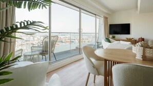 Un soggiorno moderno con un'ampia finestra, una televisione a schermo piatto e un'area pranzo con tavolo e sedie.