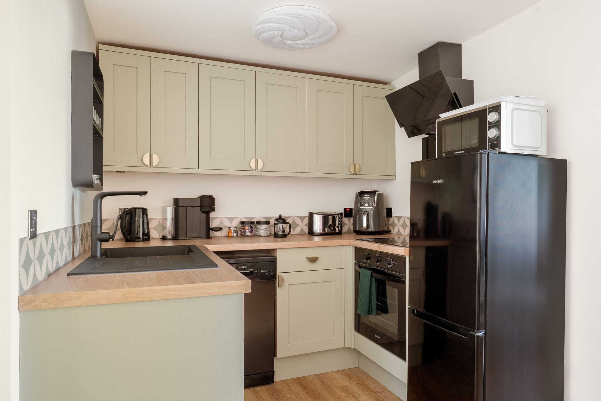 A compact kitchen with a dishwasher, oven, microwave, and coffee maker.