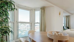 Una stanza moderna con un tavolo da pranzo, sedie, una ciotola decorativa e ampie finestre con vista su un corpo d'acqua.