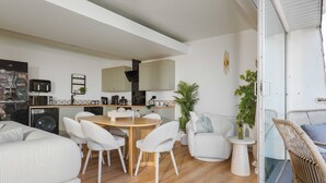 Una cucina moderna con zona pranzo, arredi bianchi e vista sull'esterno.